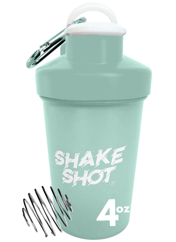 A green mini shaker bottle labeled 'Shake Shot' being held by a hand, with a carabiner attached to it, against a colorful background.